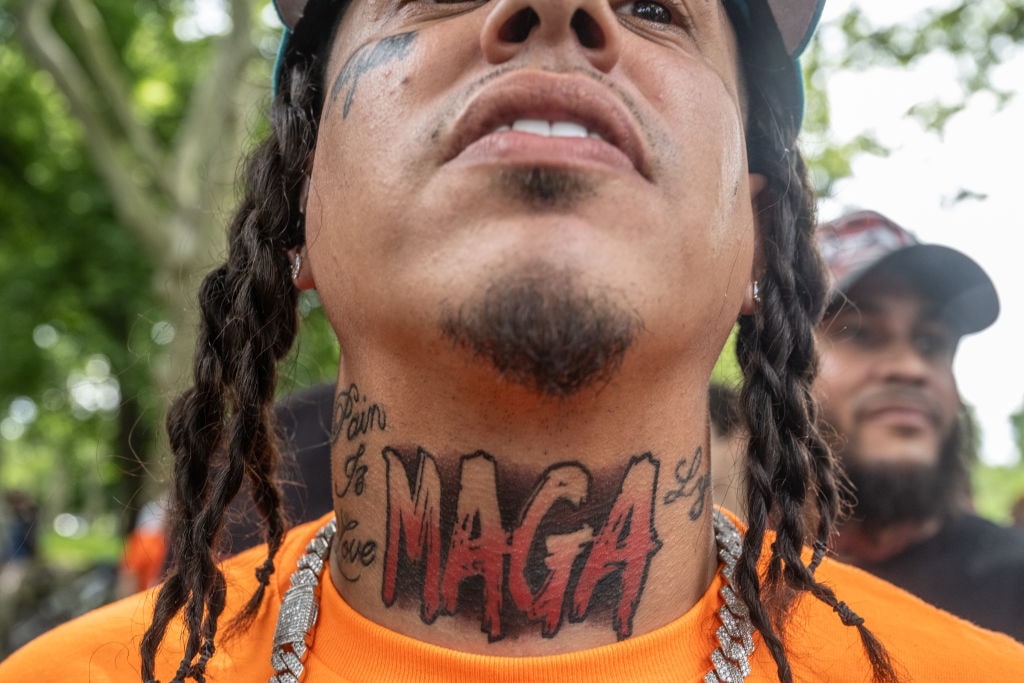 Donald Trump Visits The Bronx While On Trial In Hush-Money CaseNEW YORK, NEW YORK - MAY 23: A person has "MAGA" tattooed on his neck as he stands with supporters of former U.S. President Donald Trump as they gather outside of the Crotona Park rally venue in the Bronx borough on May 23, 2024 in New York City. Trump's visit to the deep blue borough of the Bronx is seen as a way to make inroads with Black and Hispanic voters. His visit coincides with the end of his hush money trial. (Photo by Stephanie Keith/Getty Images)